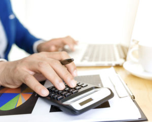 Man using calculator and computer at a desk
